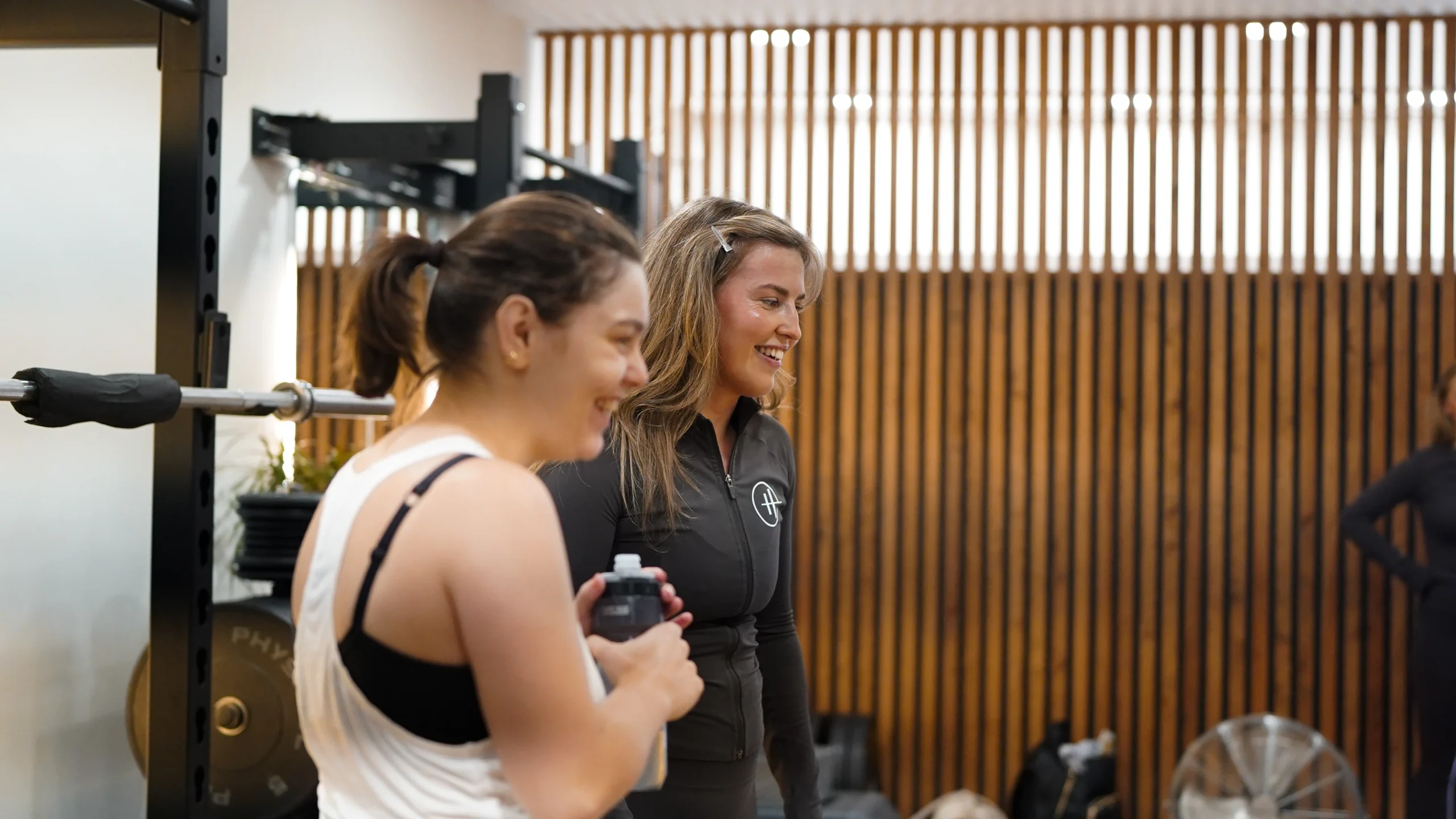 Her Fitness trainer and member together with squat rack on background